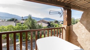 A balcony with a view of mountains, a wooden ceiling, and a white table. - "Le Quattru" Apartment with Sea View, Wi-Fi, and Air Conditioning (Appietto)