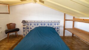 A small attic room with a bed, a chair, a desk, and a window. - “Le Cinque” Apartment with Sea View, Wi-Fi, and Air Conditioning (Appietto)