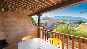 A balcony with a table and chairs, a view of a village, and mountains in the distance. - “Le Cinque” Apartment with Sea View, Wi-Fi, and Air Conditioning (Appietto)