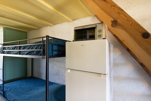 Un dormitorio con literas, un microondas y un refrigerador.