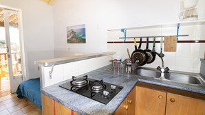 A kitchen with a gas stove, sink, and hanging pots. - “Le Cinque” Apartment with Sea View, Wi-Fi, and Air Conditioning (Appietto)