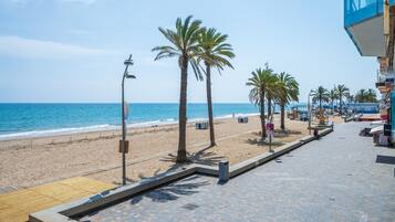 A beachside walkway with palm trees, a wooden deck, and a view of the ocean.