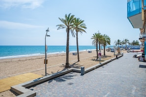 A beachside walkway with palm trees, a wooden deck, and a view of the ocean.