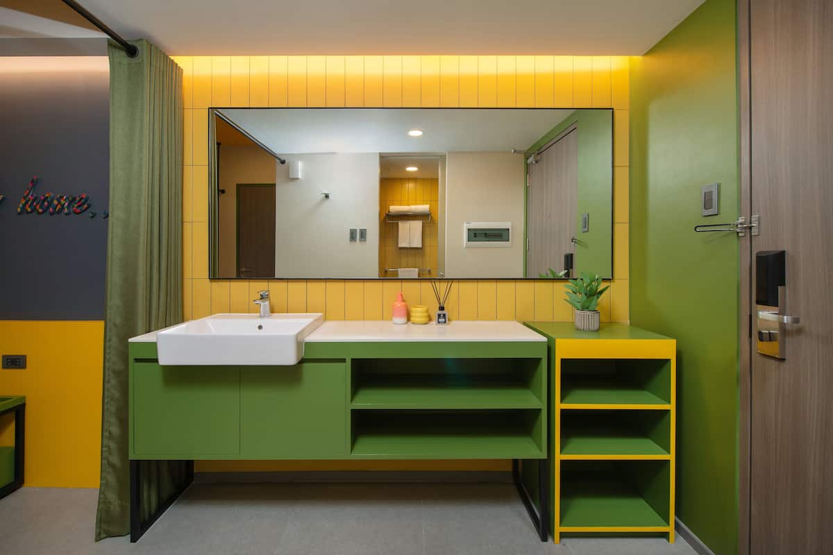 Casa de banho com toucador verde, lavatório branco e espelho em cima.
