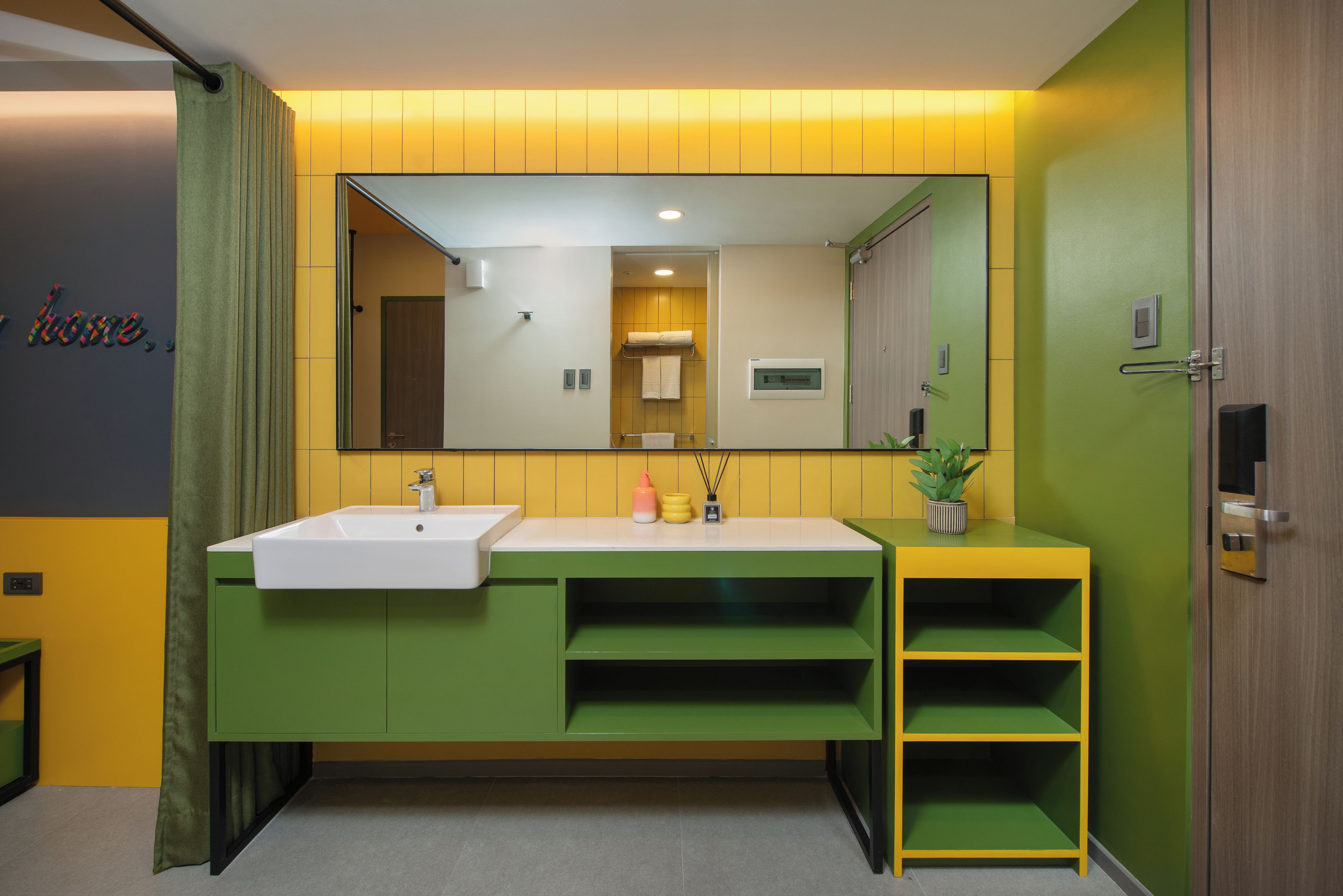 Un baño moderno con un tocador verde, un lavabo blanco y un espejo.