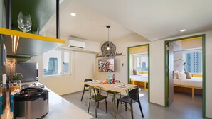 A modern kitchen with a built-in stove, dining table, and chairs. There is a window with a city view, a bed with a view, and a wall with a picture. - lyf Malate Manila managed by The Ascott Limited (Manila)