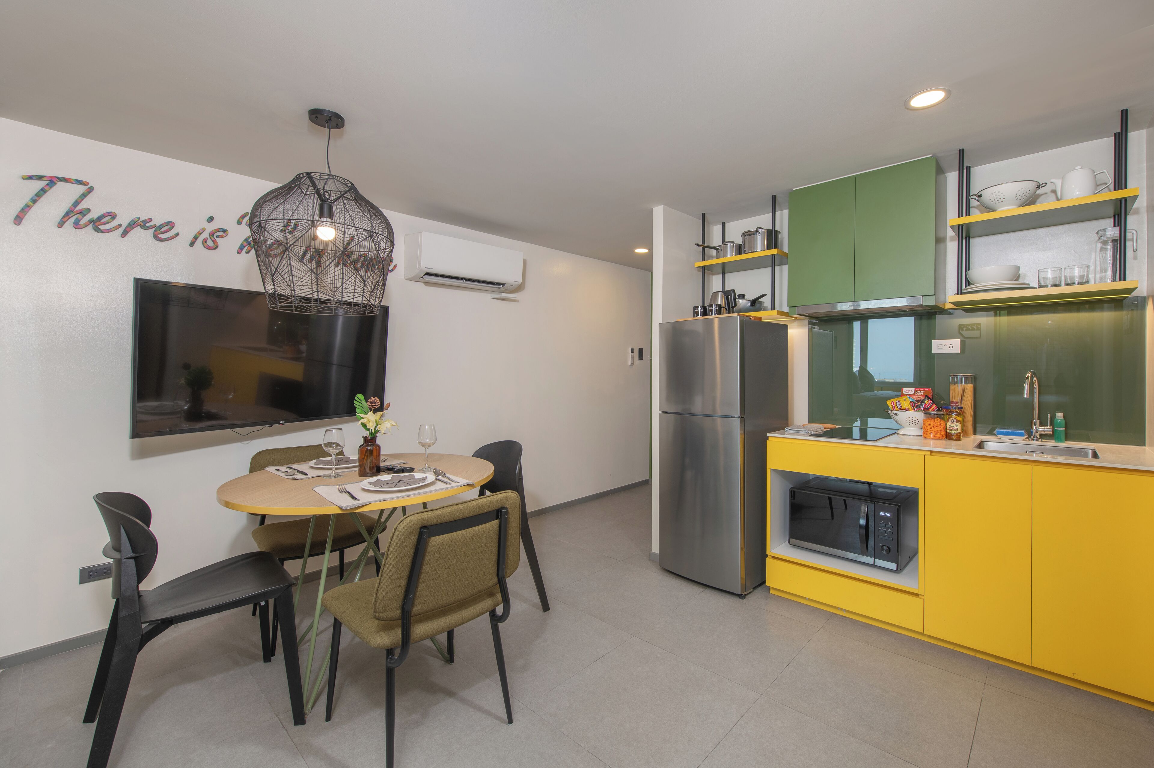 A modern kitchen with a built-in microwave, a stainless steel refrigerator, and a yellow countertop.
