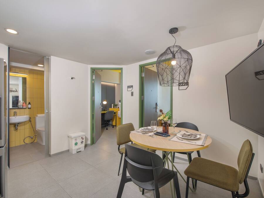 A modern kitchen with a dining area, a large flat-screen TV, and a unique pendant light.