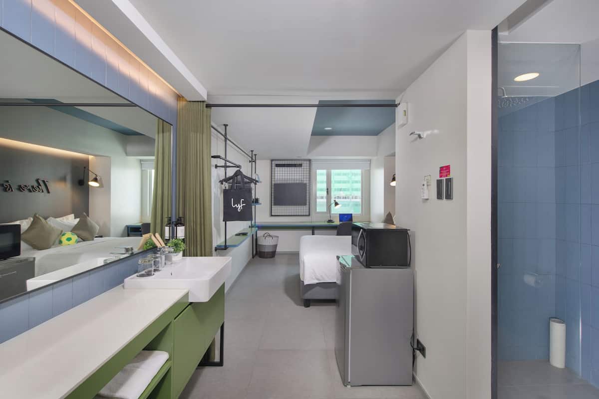 Casa de banho de hotel moderna com um espelho grande, duas lavatórios, chuveiro e uma pequena janela.
