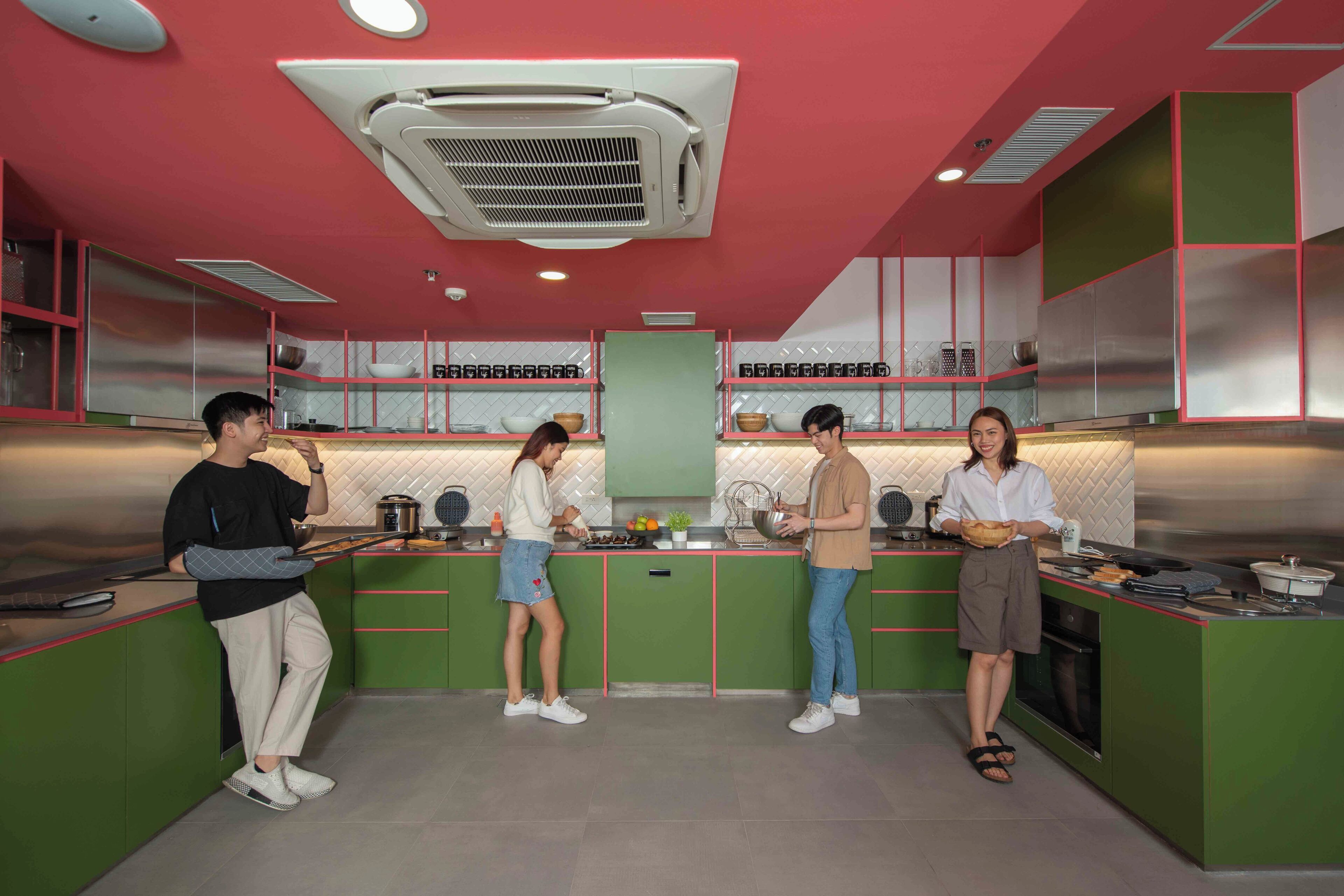 Una cocina moderna con armarios verdes, una isla central y un protector contra salpicaduras de acero inoxidable.
