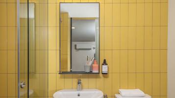 Un baño con cabina de ducha de vidrio, un lavamanos blanco y un inodoro.