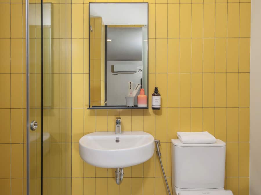 Un baño con cabina de ducha de vidrio, un lavamanos blanco y un inodoro.