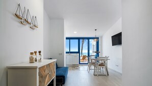 A modern interior with a dining area, kitchen, and a view through a large window. - Apartment 'Calafellmar Loft' with Sea View, Wi-Fi and Air Conditioning (Calafell)
