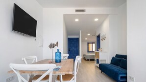A modern living room with a dining area, a blue sofa, and a TV mounted on the wall. - Apartment 'Calafellmar Loft' with Sea View, Wi-Fi and Air Conditioning (Calafell)