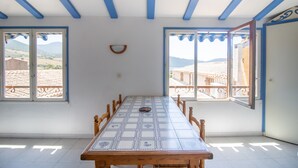 A dining area with a table, chairs, and large windows with a view of the landscape. - "Le Zini" Apartment with Sea View, Wi-Fi, and Air Conditioning (Appietto)