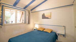 A bedroom with a bed, a nightstand, a lamp, a window with curtains, and a wall-mounted shelf. - "Le Zini" Apartment with Sea View, Wi-Fi, and Air Conditioning (Appietto)