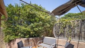 An outdoor patio with a table and two chairs, surrounded by greenery and a wooden fence. - "Le Zini" Apartment with Sea View, Wi-Fi, and Air Conditioning (Appietto)
