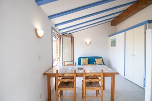 A dining area with a wooden table and chairs, a blue sofa, and a mirror on the wall.