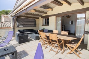 Un patio al aire libre con mesa y sillas de madera, un sofá y una parrilla.