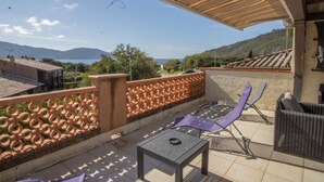 A terrace with a view of the sea, a table, chairs, and a decorative fence.