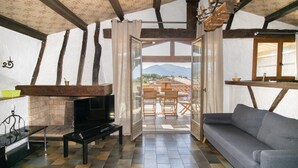 A cozy living room with a fireplace, a sofa, a TV, and a dining area with a view of the mountains.