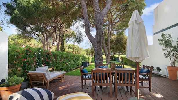 An outdoor patio with a wooden table and chairs, a white umbrella, and potted plants. - Vacation Home "Vilamoura Com Piscina E Wifi" with Private Pool, Terraces & Wi-Fi (Vilamoura)