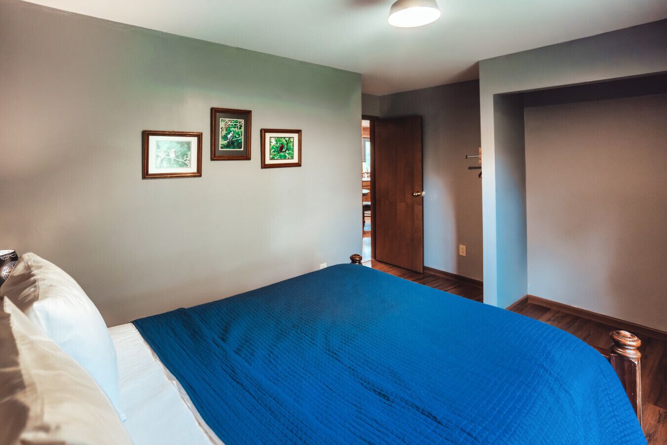 Ein Schlafzimmer mit einem Bett, einer Tür und drei gerahmten Bildern an der Wand.