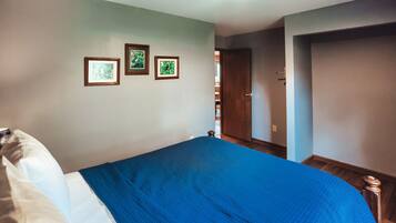 Ein Schlafzimmer mit einem Bett, einer Tür und drei gerahmten Bildern an der Wand.