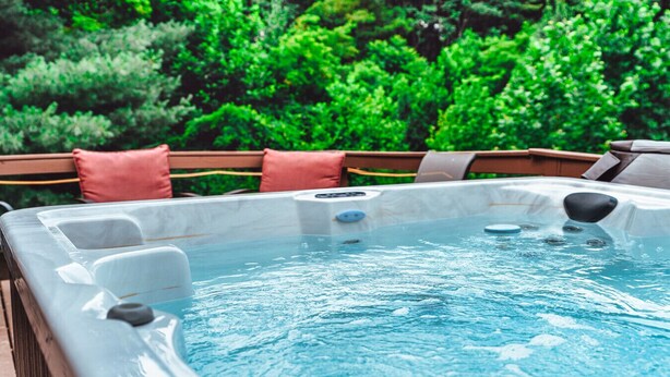 A hot tub with a wooden deck and red cushions. - Romantic Cabin | King Bed | Hot Tub | Spring Vibes (Rockbridge)