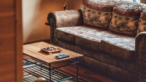A cozy living room with a sofa, a small table, a lamp, and a framed picture on the wall. - Romantic Cabin | King Bed | Hot Tub | Spring Vibes (Rockbridge)