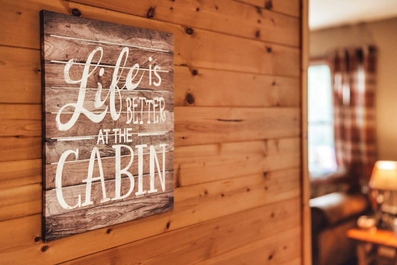 A wooden cabin wall with a sign that reads "Life is better at the cabin."