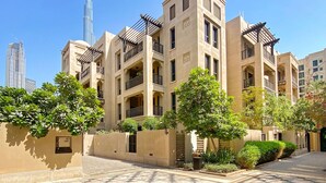 A courtyard with a checkered floor, surrounded by beige buildings with balconies and greenery. - Silkhaus Zaafaran, Downtown Dubai (Dubai)
