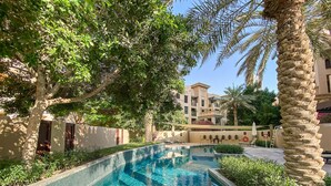 A swimming pool with clear blue water, surrounded by lush greenery and palm trees. - Silkhaus Zaafaran, Downtown Dubai (Dubai)