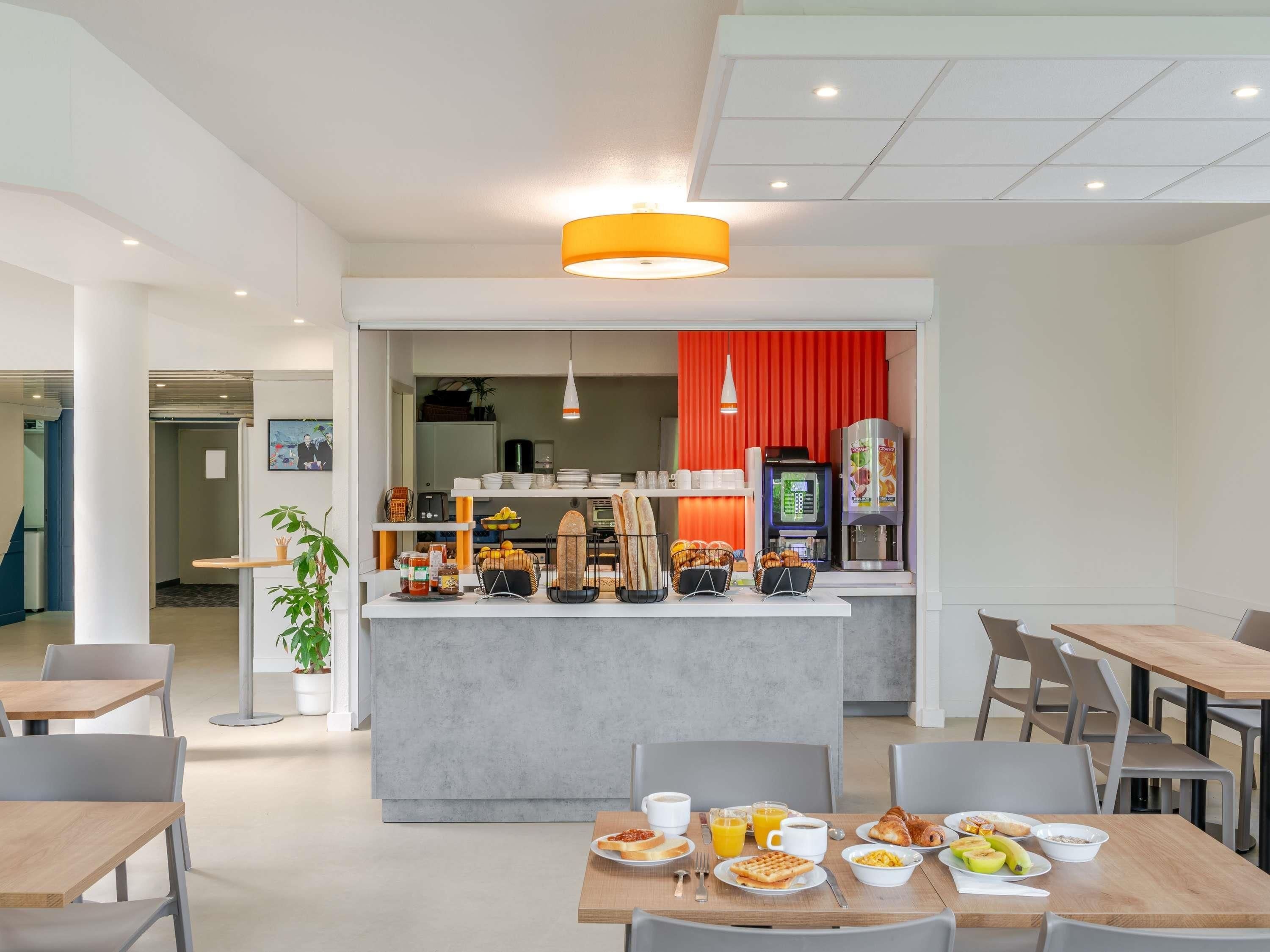 A modern breakfast area with a central counter, seating arrangements, and a vending machine.