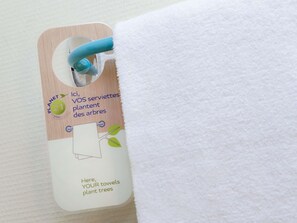 Una etiqueta prendida a una toalla blanca, con un fondo de madera y un asa azul.