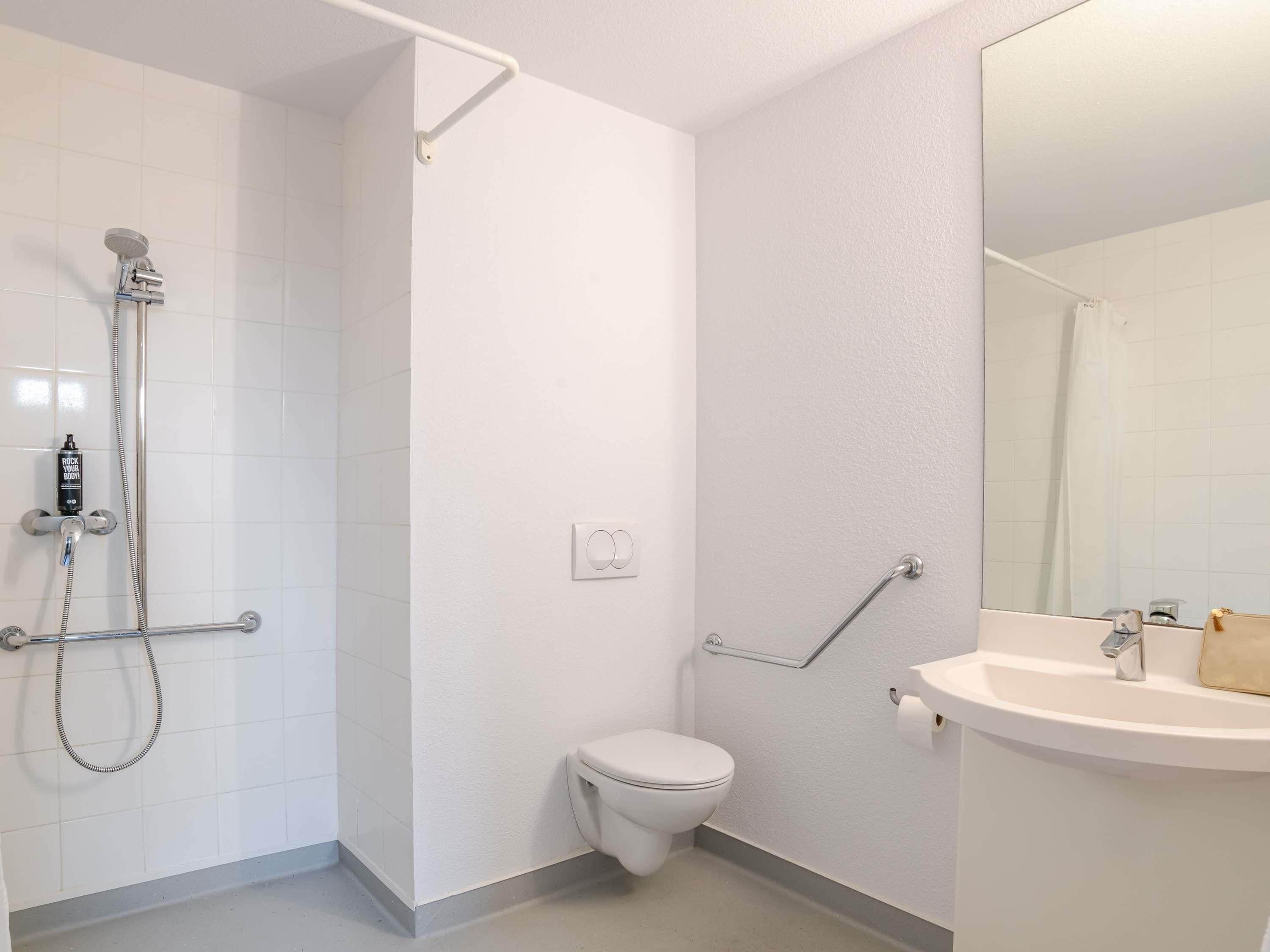 Une salle de bain avec douche, toilettes et lavabo.
