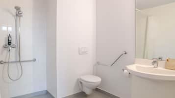Een badkamer met een douche, toilet en wastafel.