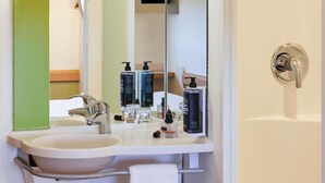 A bathroom with a sink, mirror, and toiletries.