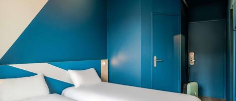 A room with a bed, a door, and a suitcase.