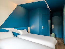 Una habitación con una cama, una puerta y una maleta.