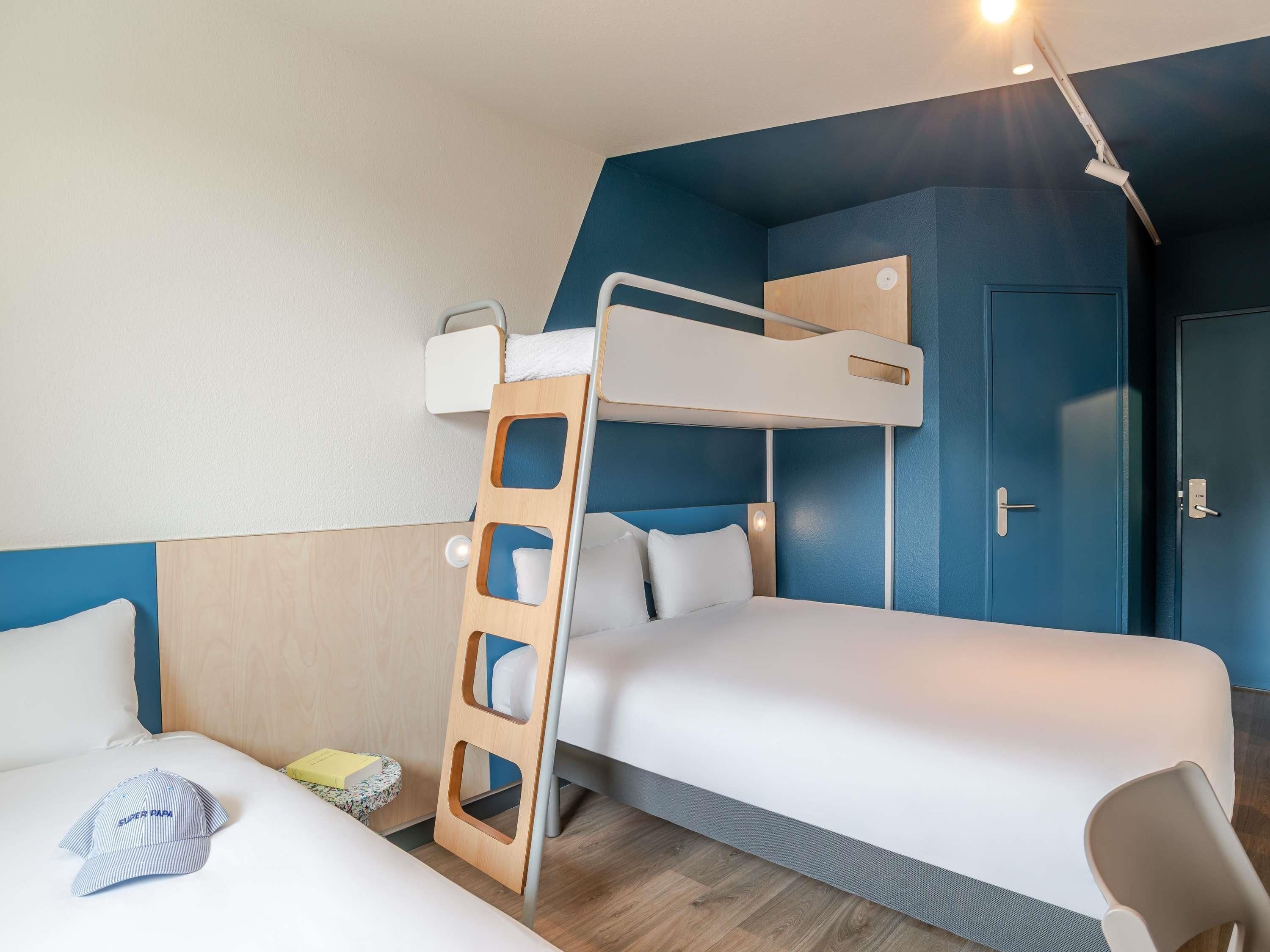 A bunk bed room with a ladder, a desk, and a door.