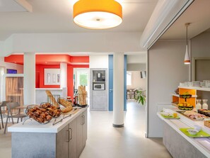 Una cocina moderna con una isla central, un comedor con sillas y una lámpara colgante luminosa.