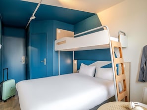 A bunk bed with a ladder, a suitcase, and a round table with a chair.