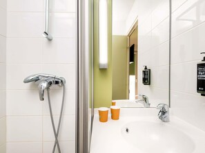 Un baño moderno con ducha, lavamanos y espejo.