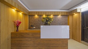A reception desk with a statue, a vase of flowers, and a geometric patterned wall. - Itsy Hotels Peak View, 300 Mts From Mall Road (Mussoorie)