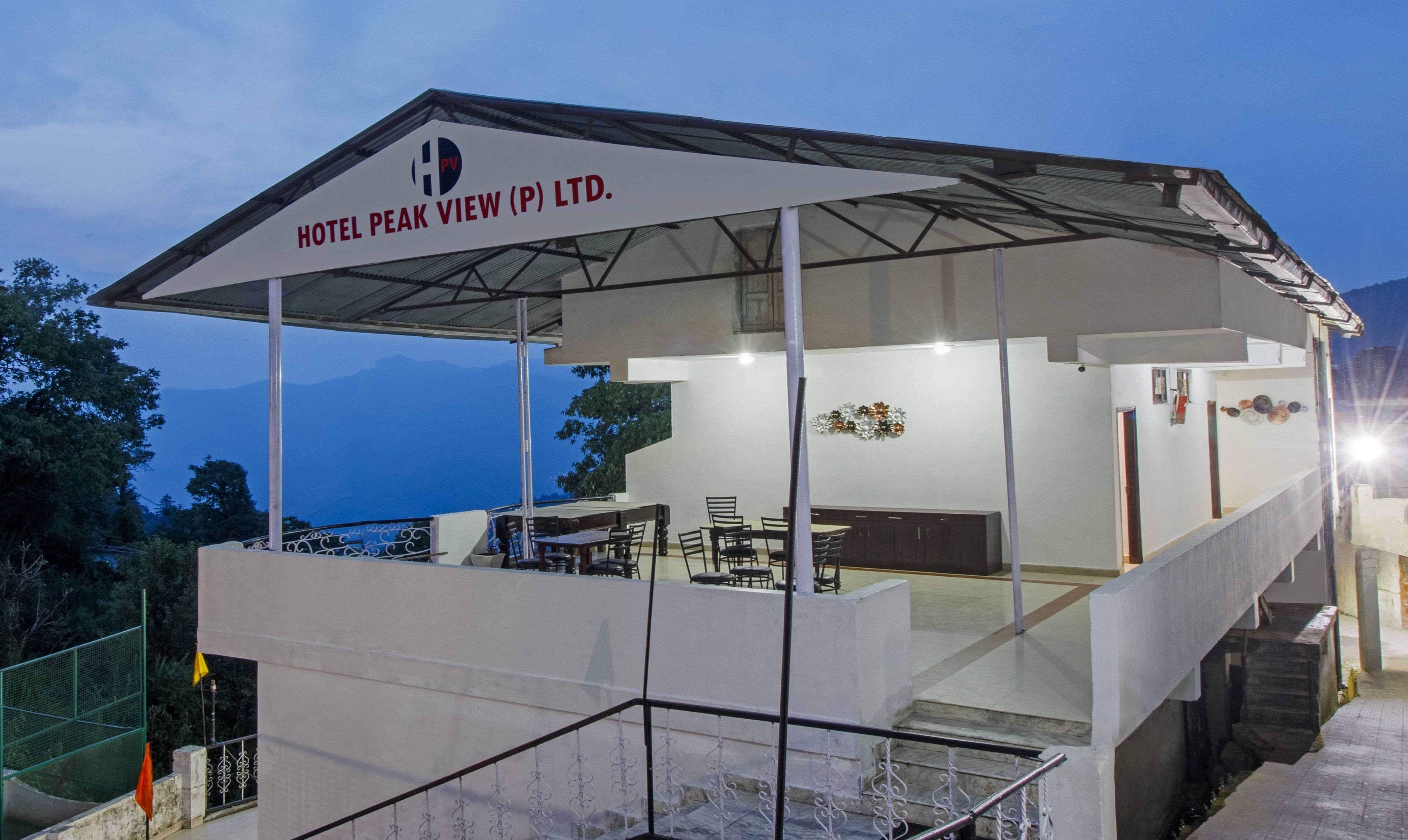 A modern hotel with a covered outdoor seating area, a staircase, and a view of the mountains.