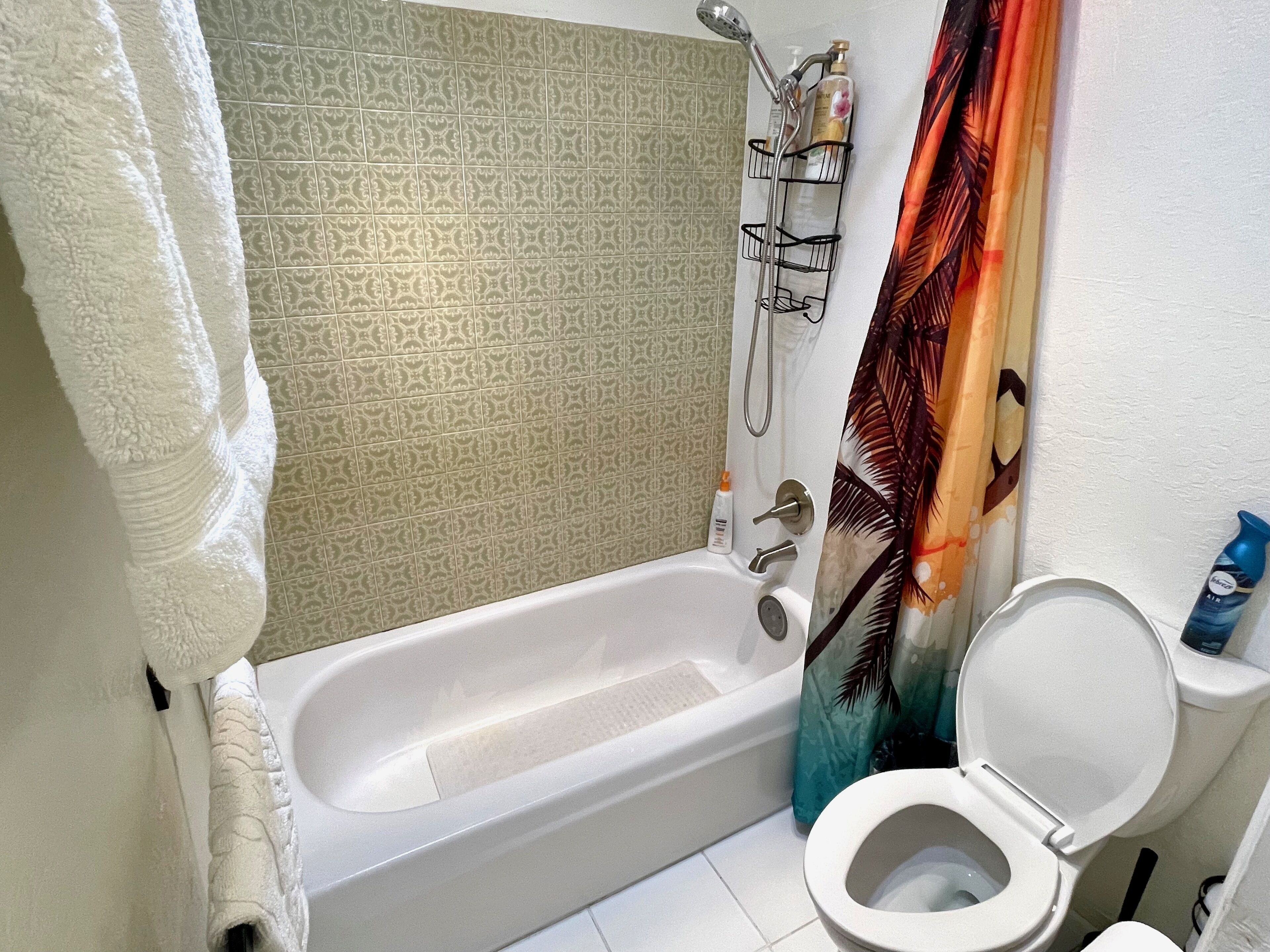 A bathroom with a bathtub, toilet, shower, and patterned tiles.