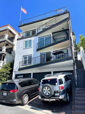 A multi-story residential building with a garage parking two SUVs. - SurfView VR: Best Ocean and Pier View, 5 mins to Beach, Cozy Patio, Pet Friendly (San Clemente)