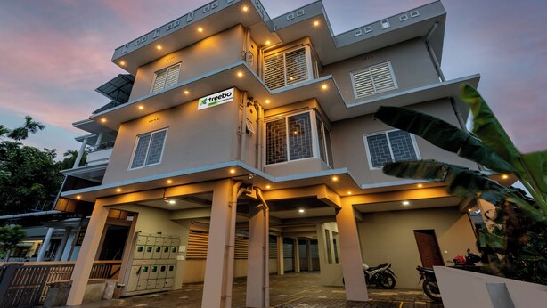 A modern multi-story building with a flat roof, multiple balconies, and a sign indicating a gaming arcade. - Treebo Dreams Arcade (Aluva)