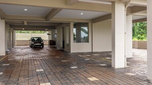 A covered parking area with a wet floor, a car, and a view of greenery outside. - Treebo Dreams Arcade (Aluva)